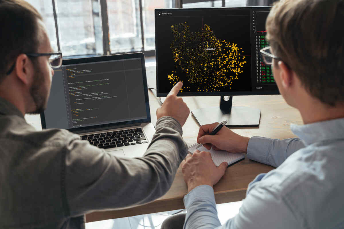 Closeup of two men data science specialists working at office together, analyzing big data on screen.